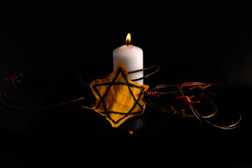 Holocaust memory day. Arbed wire and burning candle on black background - Powered by Adobe