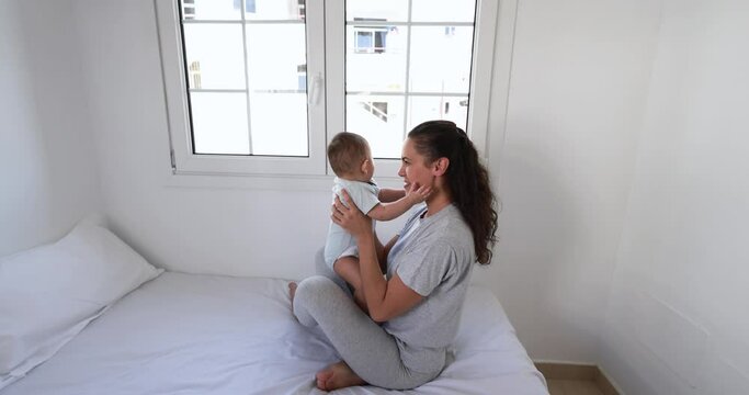 Young mom having fun with her son in bed at home 