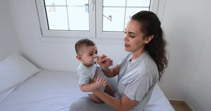 Young mom having tender moment with her son in bed at home 