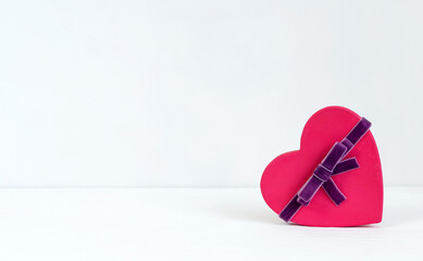 A small heart shaped box with ribbon. Gift on white background. Template with copy space for Valentine's Day greetings.