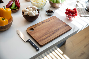 Cutting board, knife and ingredients on kitchen counter, food preparation.