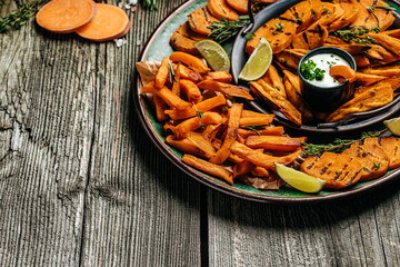 Set of homemade baked sweet potato fries with lime. Sweet potato fries with herbs on wooden background banner, menu, recipe place for text, top view
