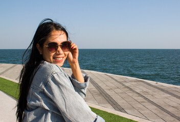 Asian young lady sitting smiling and enjoying the sea view