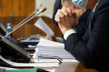 Hands of men - officials, lawyers, deputies or businessmen sitting at a table with documents,...
