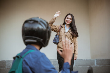 Smiling woman happily waving to people riding motorbikes