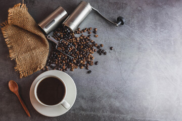 Hand coffee grinder and coffee beans and coffee cup on table.
