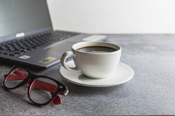 Coffee cup on desk with laptop and glasses