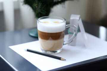 Third-layered cappuccino with foam in a transparent cup, on a piece of office paper.