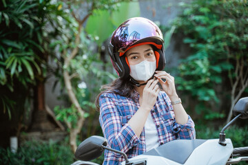 Woman in a mask preparing to tie helmet safety strap