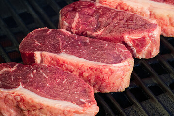 grilling raw steaks on gas grill and shot with selective focus.