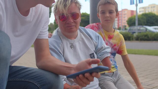 Woman with congenital malformations of the upper and lower endpoints on a skateboard surrounded by friends using the phone.