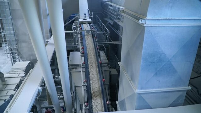 Looking down at the conveyor belt transporting white clay for future processing. Modern kaolin factory.