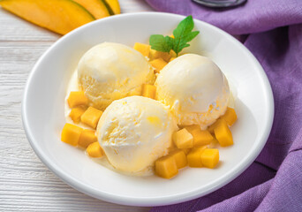 Three balls of mango ice cream in a plate on a light background.