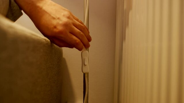 Light is On - Male hand switch on a button on a night light at home