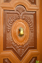 Porta de madeira de uma grande casa pintada em castanho brilhante com uma aldrava em forma de mão datada em bronze 
