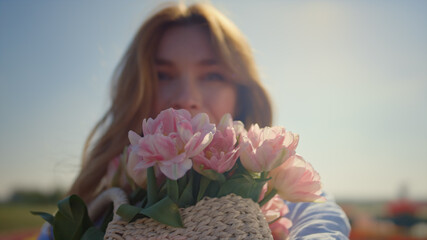 Portrait of beautiful woman smelling gentle flower bouquet in sun reflection.