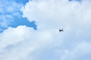 Fototapeta na wymiar The quadcopter is flying in the sky. Cloudy sky, large white clouds, a cloud is coming, bad weather. Horizontal background.