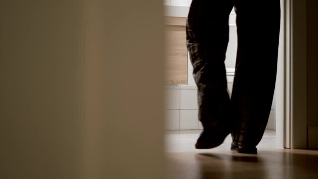 Adult man in pajamas walk slowly to a toilet at home in the night