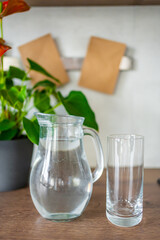 Jug with clear cold water on kitchen table in the home