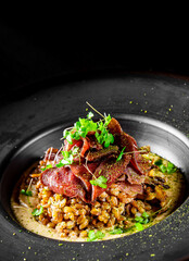 Spelt with meat in black plate