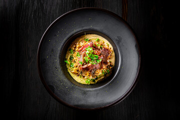 Spelt with meat in black plate