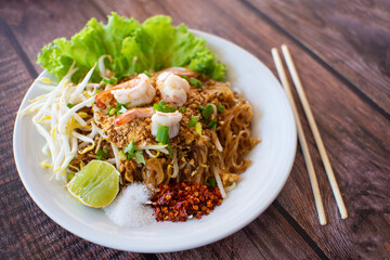 Pad Thai Thai food is spicy in a white plate on a wooden floor with copy space