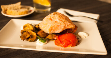 simmered slice of salmon with tomato spinon and coconut sauce on a white plate