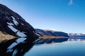 Fototapeta na wymiar Beautiful mountains with a snow and reflection in the Atlantic ocean. Westfjords, Iceland.
