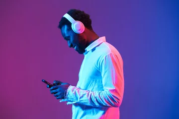 Poster Young black man listening music with headphones and cellphone © Drobot Dean
