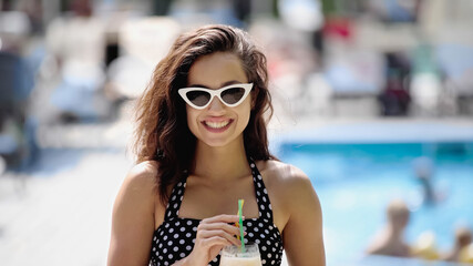 happy young woman in sunglasses holding cocktail