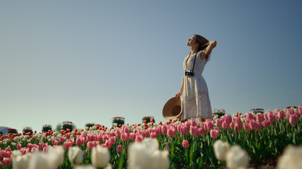 Camera moving around girl staying in tulip field. Woman enjoying summer day. 