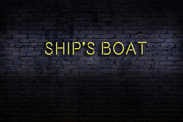 Night view of neon sign on brick wall with inscription ship's boat