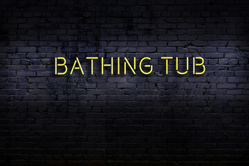 Neon sign. Word bathing tub against brick wall. Night view