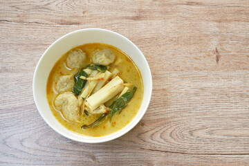 spicy boiled slice fresh coconut shoot with fish ball in green curry soup on bowl