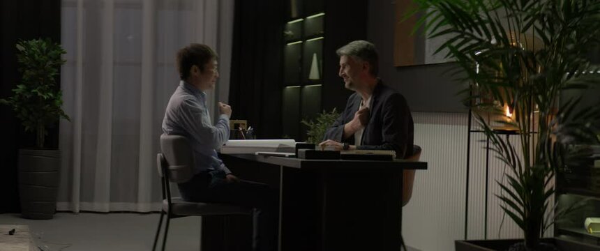 Two colleagues performing bizarre chant ritual late in the evening in the office, thumping their chests and humming. Shot with 2x anamorphic lens