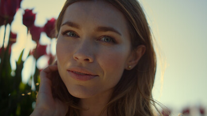 Happy woman touching face in tulip sunlight field. Closeup smiling lady outdoor 