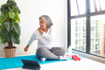 Asian elderly woman sit exercise at home Do yoga poses according to an online fitness teacher via...