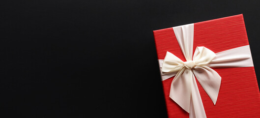 Red gift box  with luxury bow on dark background with copy space, Christmas gift