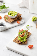 Vegeterian breakfast with sandwiches with avocado paste on marble plate. Food composition with levitation of black sesame seeds