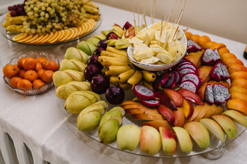 Tropical healthy fresh fruits assortment on a plate. Fruit platter with fresh grapes, apple, pineapple, mango and pitaya. Colorful Fruit tray best good food for party and holidays table. Top view.