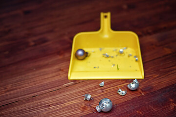 Broken fragile Christmas balls lay on wooden floor, sweep damaged Christmas ornaments with sweeping...