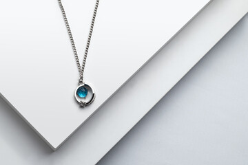 Fototapeta premium Silver chain necklace with blue diamond pendant on white background