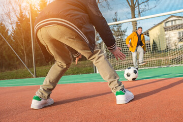 Father and son playing soccer ball on playground, dad teaches son to play on football field, family...