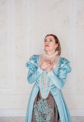 Beautiful young woman in medieval style blue dress praying