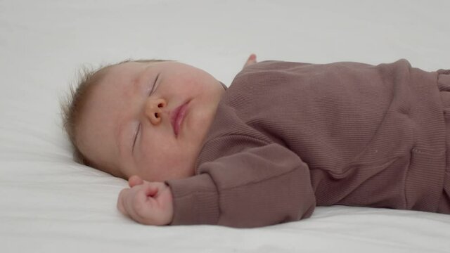 Closeup Shot Of Adorable Newborn Baby Peacefully Sleeping On Bed At Home
