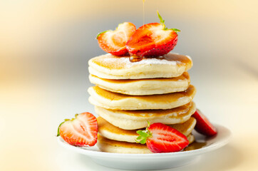 Delicious pancakes stacked with fresh sweet strawberries, topped with maple syrup