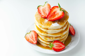 Delicious pancakes stacked with fresh sweet strawberries, topped with maple syrup