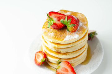Delicious pancakes stacked with fresh sweet strawberries, topped with maple syrup