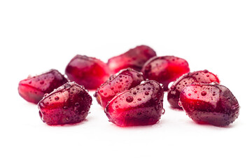 Garnet fruit seeds with water drops isolated on white background. Collection of pomegranate seeds closeup. Fresh garnet grains macro shot