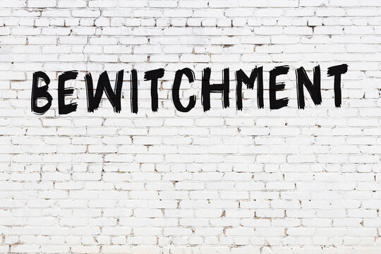 Inscription bewitchment painted on white brick wall